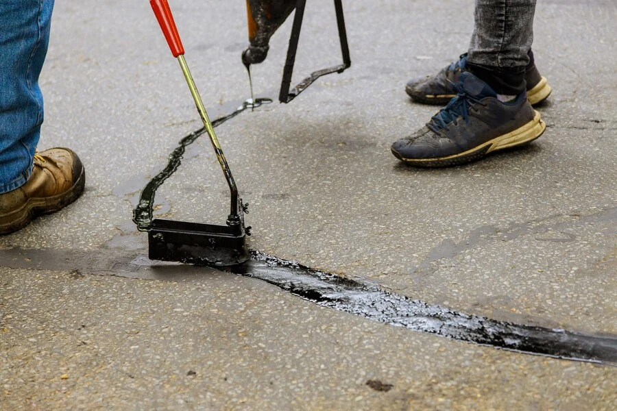 workers repairing a crack on asphalt road